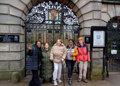 Customers on a walk round Cambridge in front of gates